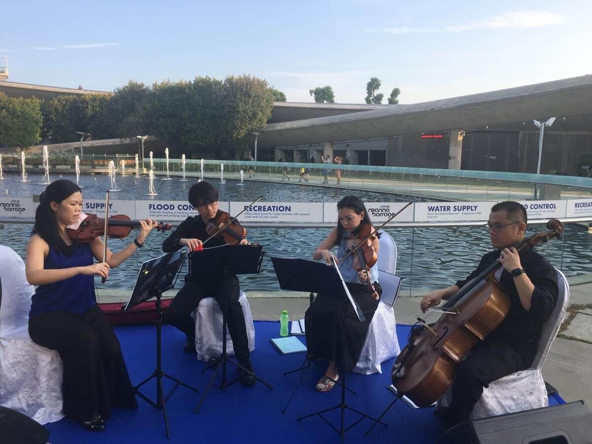 Musicians playing beside the water at an outdoor performance