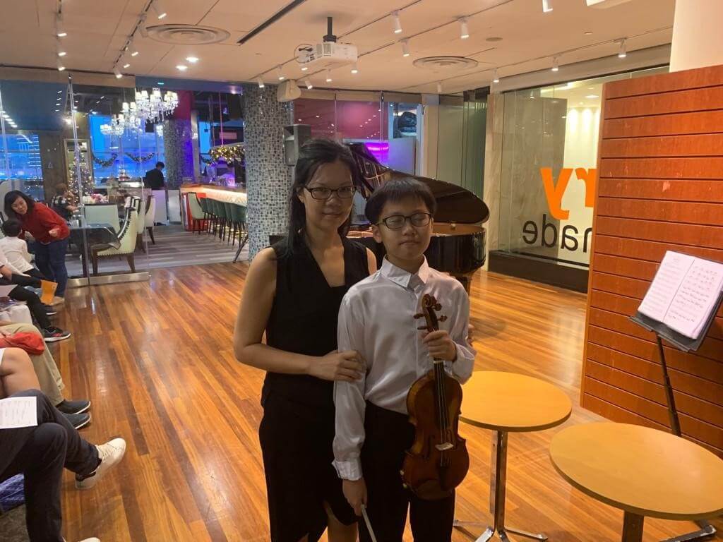 Elaine with a young violin student holding his instrument
