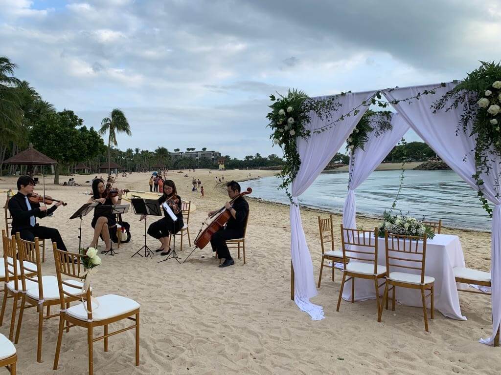 Musicians performing at an outdoor wedding by the beach